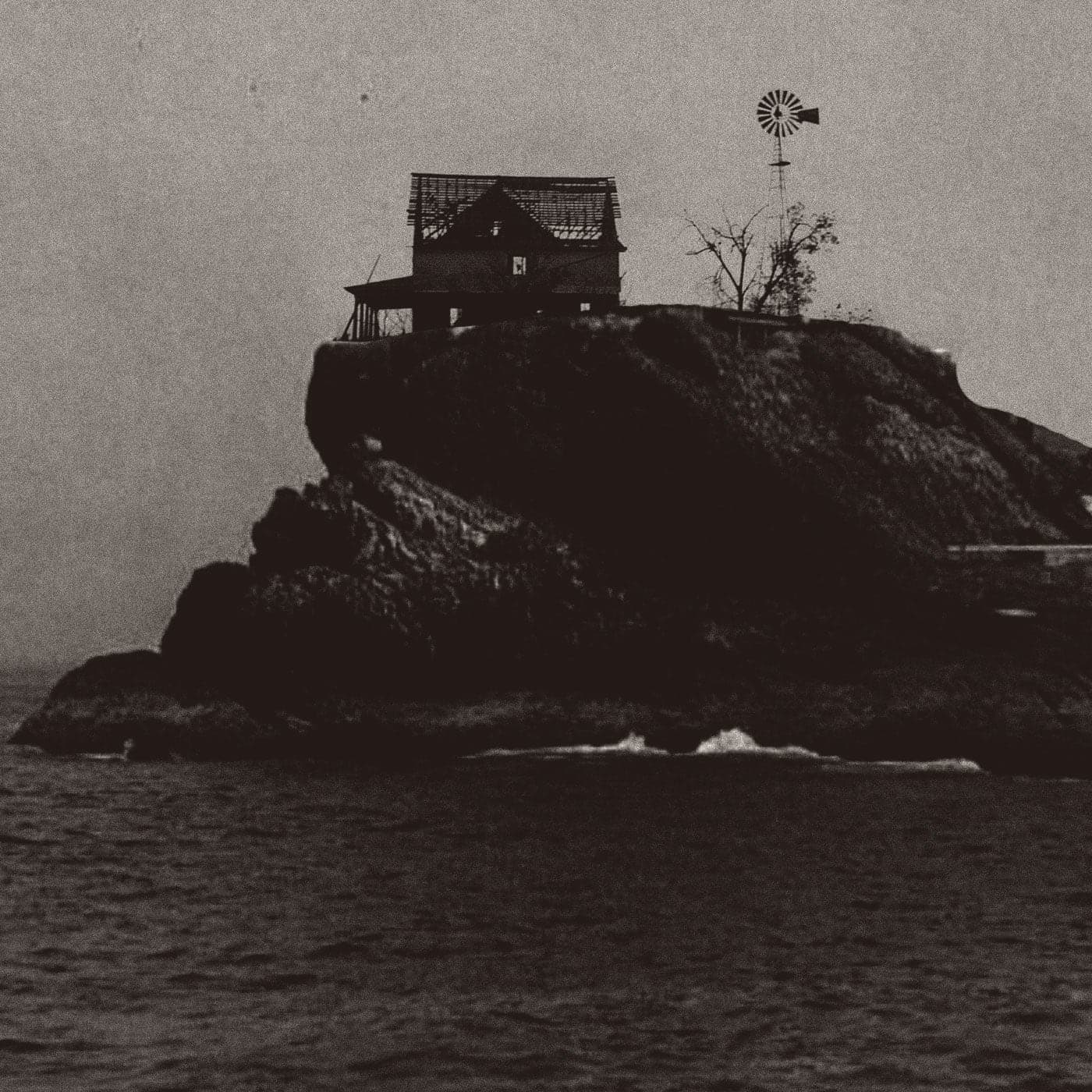 A dilapidated farmhouse sitting precariously on the edge of an island