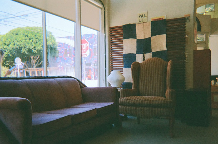 Office lounge with a sofa, a checkerboard textile hanging, and a wingback chair